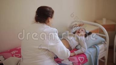 老年妇女按摩师给医院里的小女孩做腹部按摩。